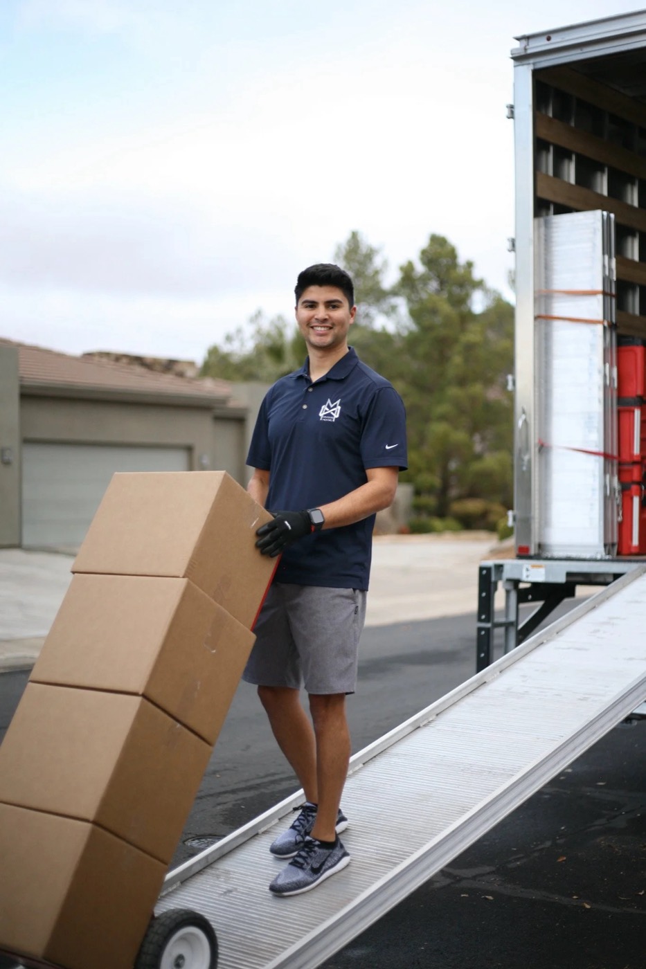 Mover wheeling a stack of boxes down the truck ramp on a dolly